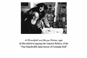 Black and white historical photograph of Al Hirschfeld and Margo Feiden from 1991, with caption text below reading: 'Al Hirschfeld and Margo Feiden, 1991. Al Hirschfeld is signing the Limited Edition of the "One Hundredth Anniversary of Carnegie Hall".